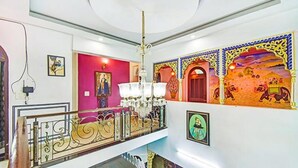 Una escalera con barandillas ornamentadas, un candelabro y coloridas obras de arte en las paredes.