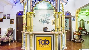 Un área de recepción con columnas ornamentales, una araña y un letrero que dice 'fab hotels'.