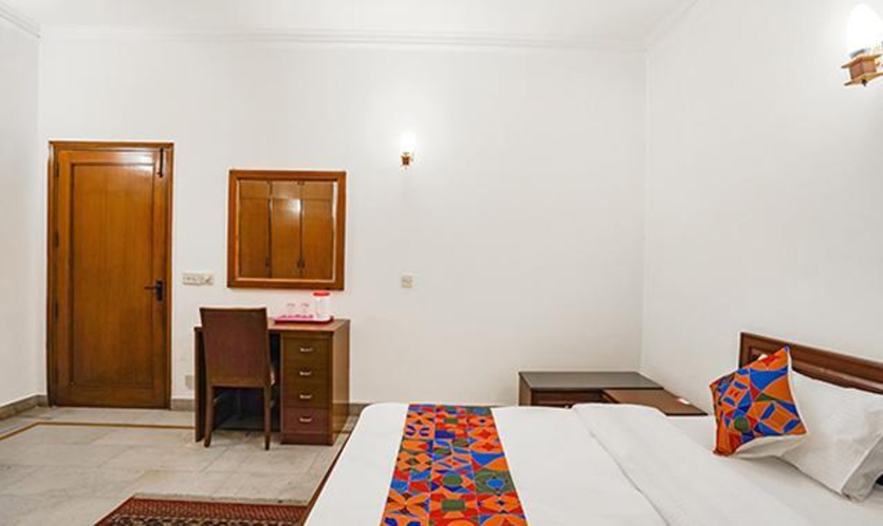 Un dormitorio con cama, escritorio, silla, armario y ventana.