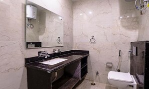 A modern bathroom with a marble wall, a black sink, a mirror, and a toilet.