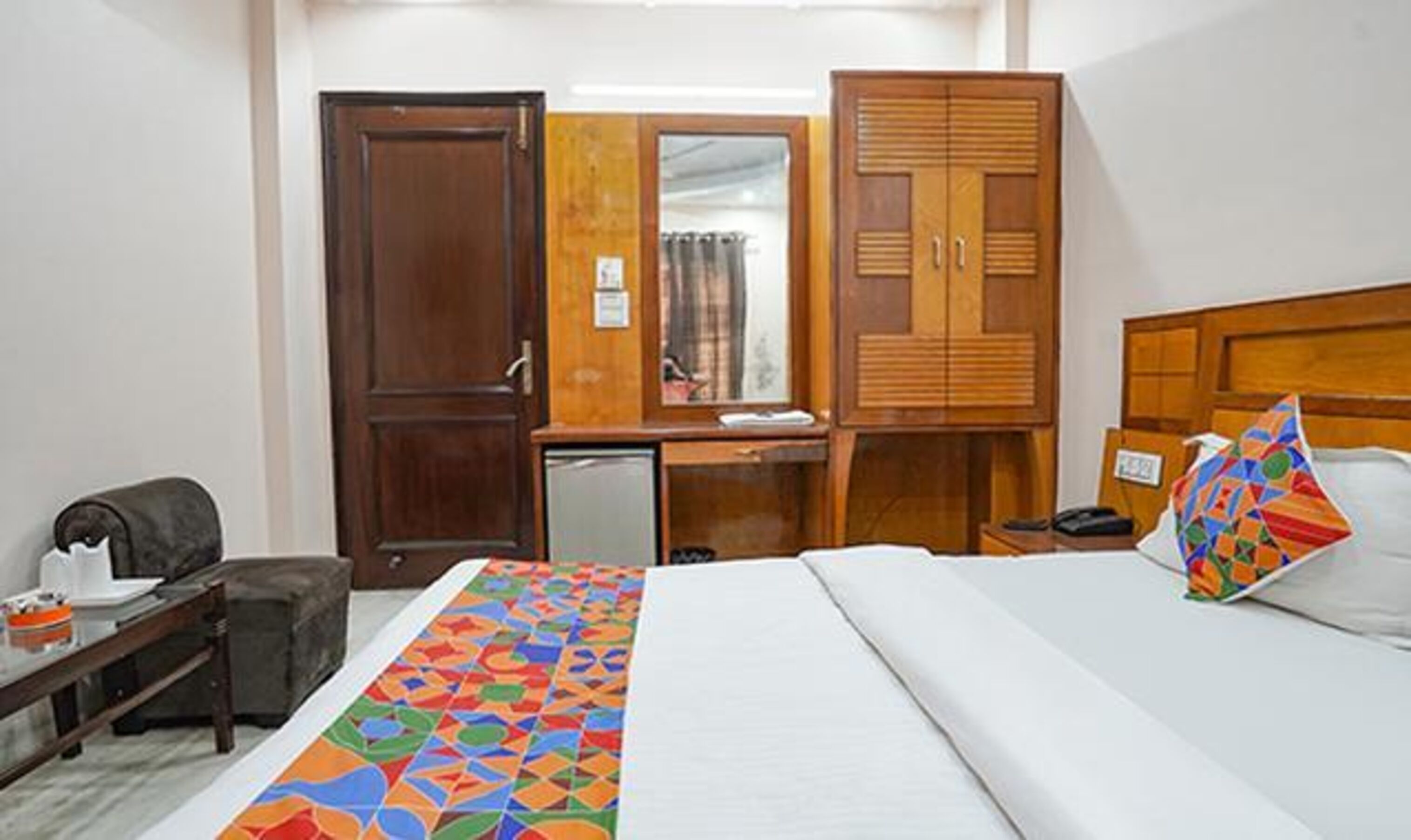 A hotel room with a bed, a desk, a wardrobe, and a small kitchenette.