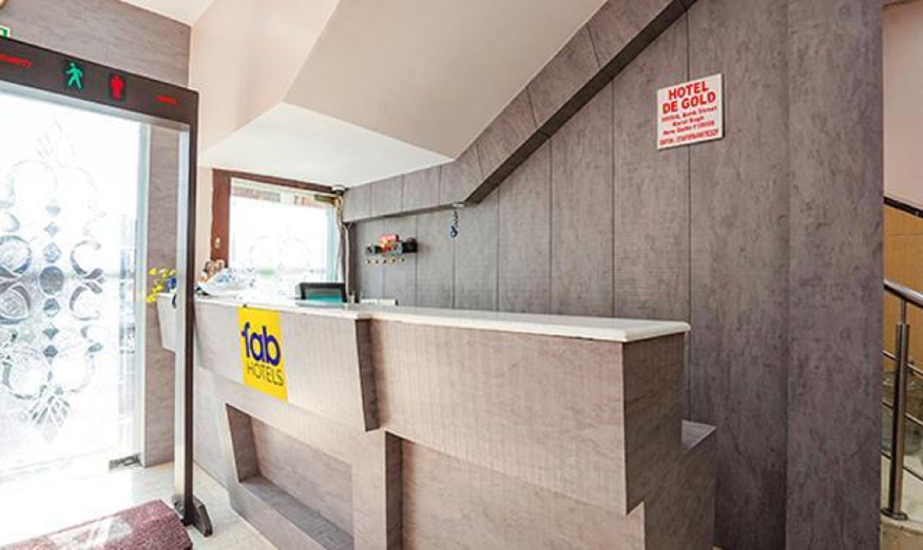 Un comptoir d’accueil d’hôtel avec une enseigne indiquant « Hôtel De Gold » et une autre indiquant « Fab Hotels ».