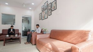 A modern office space with leather sofas, a coffee table, and framed artwork on the wall. - Via De Gold I (New Delhi)