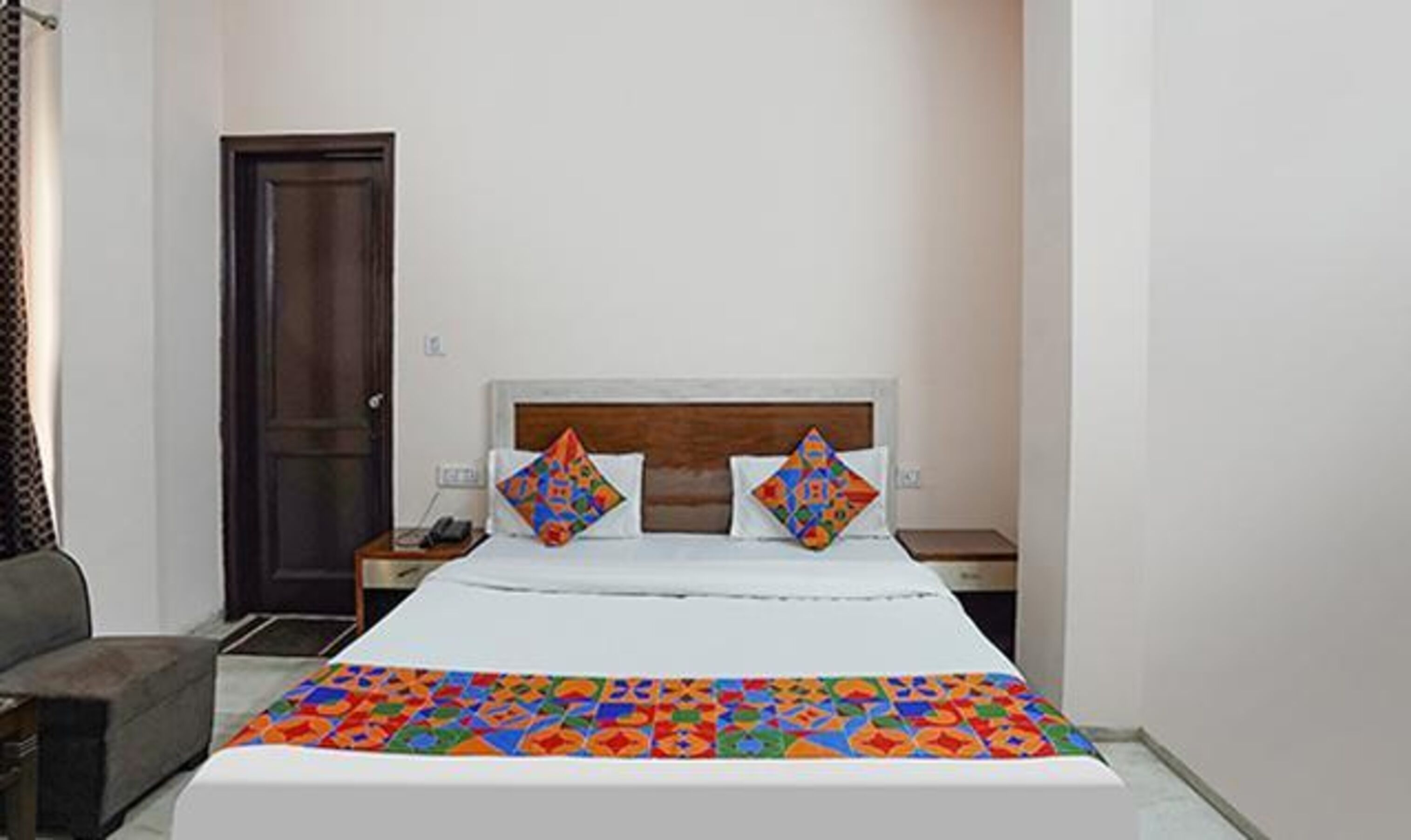 A bedroom with a bed, two pillows, a bedside table, a nightstand, and a door.