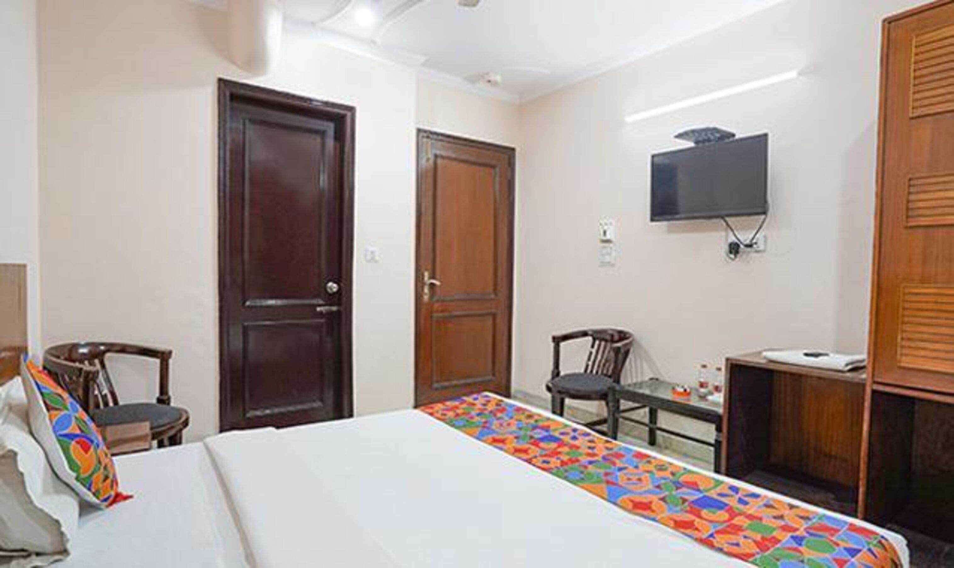 A hotel room with a bed, a desk, a chair, and a television.