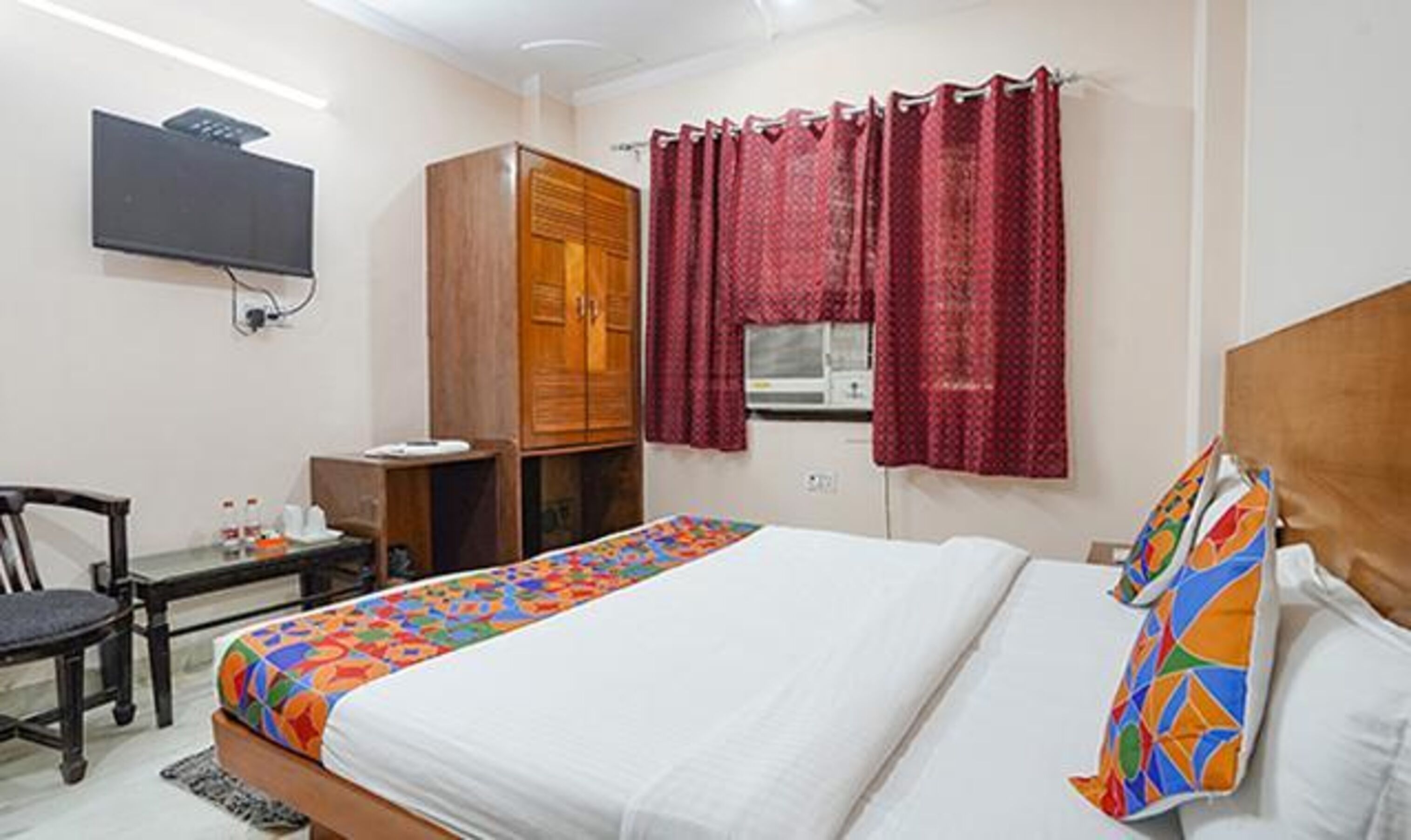 A bedroom with a bed, a desk, a chair, a TV, and a wardrobe.
