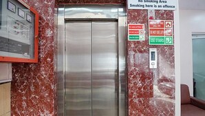 An elevator with a 'No Smoking Area' sign and emergency instructions on the wall. - Via De Gold I (New Delhi)