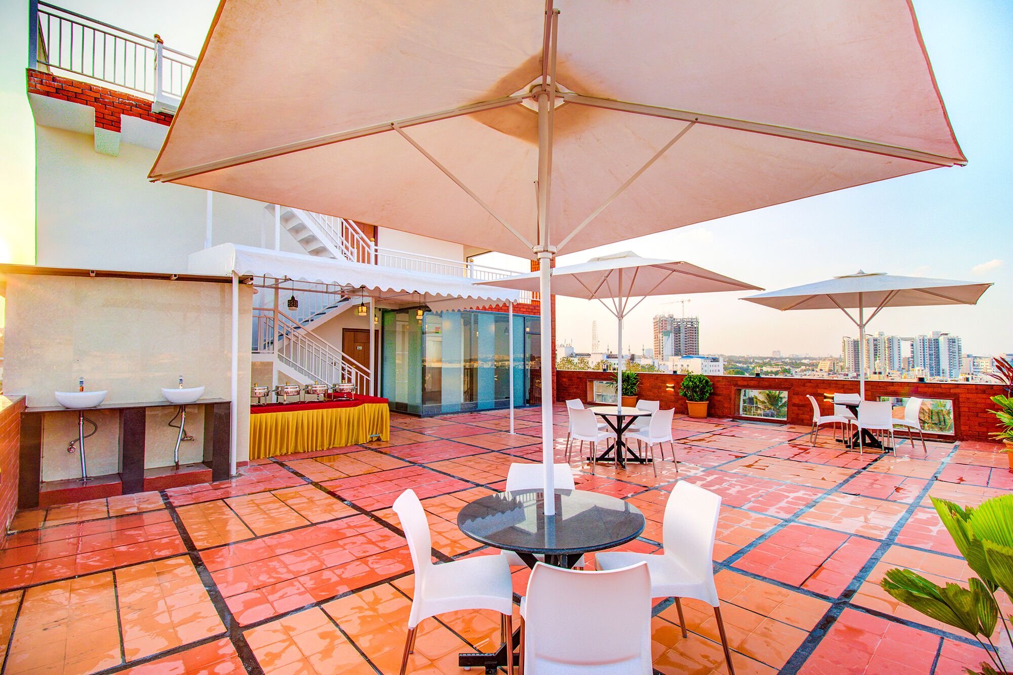A rooftop patio with outdoor seating, a bar area, and a view of the city skyline.