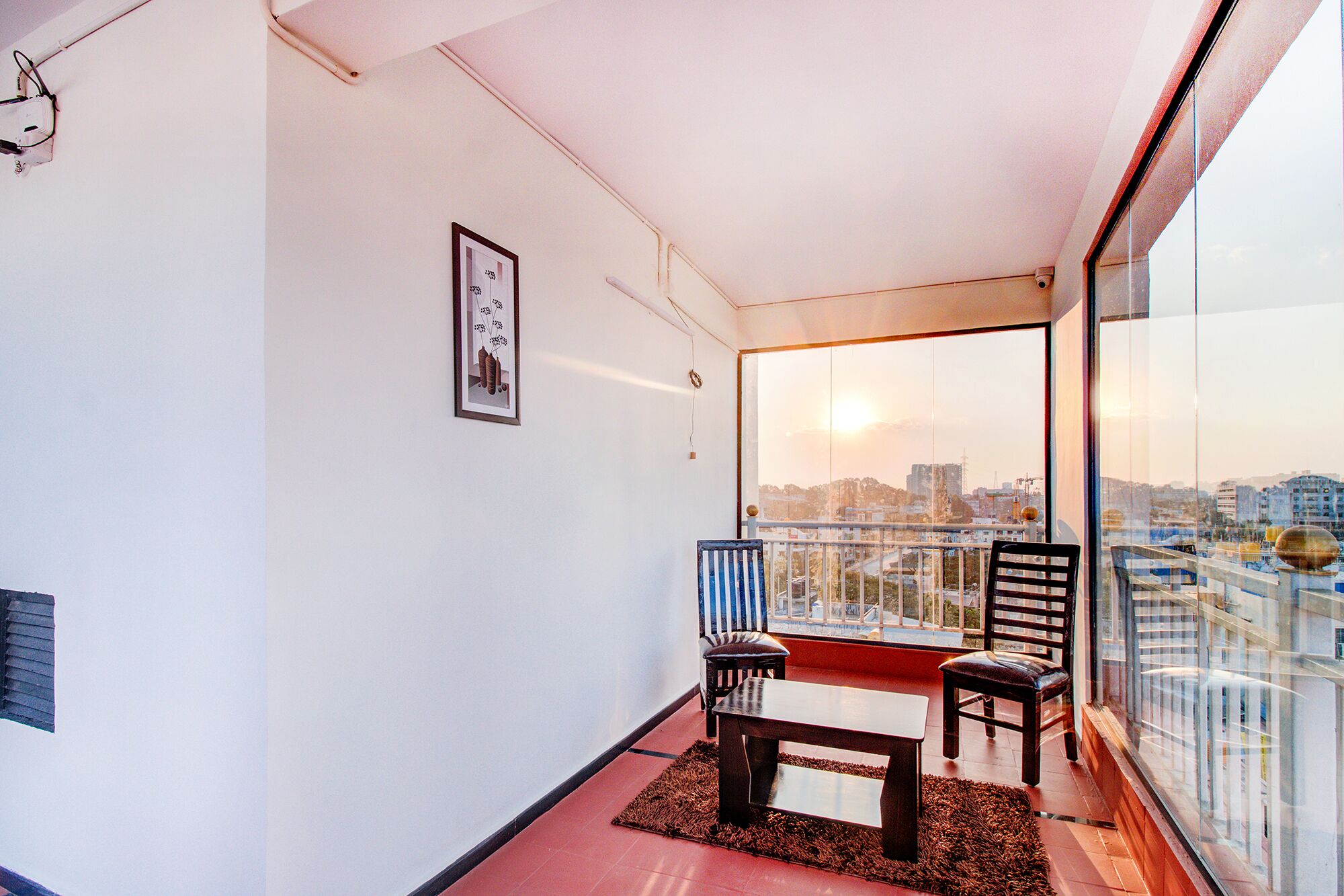 A balcony with two chairs, a small table, and a framed picture on the wall.