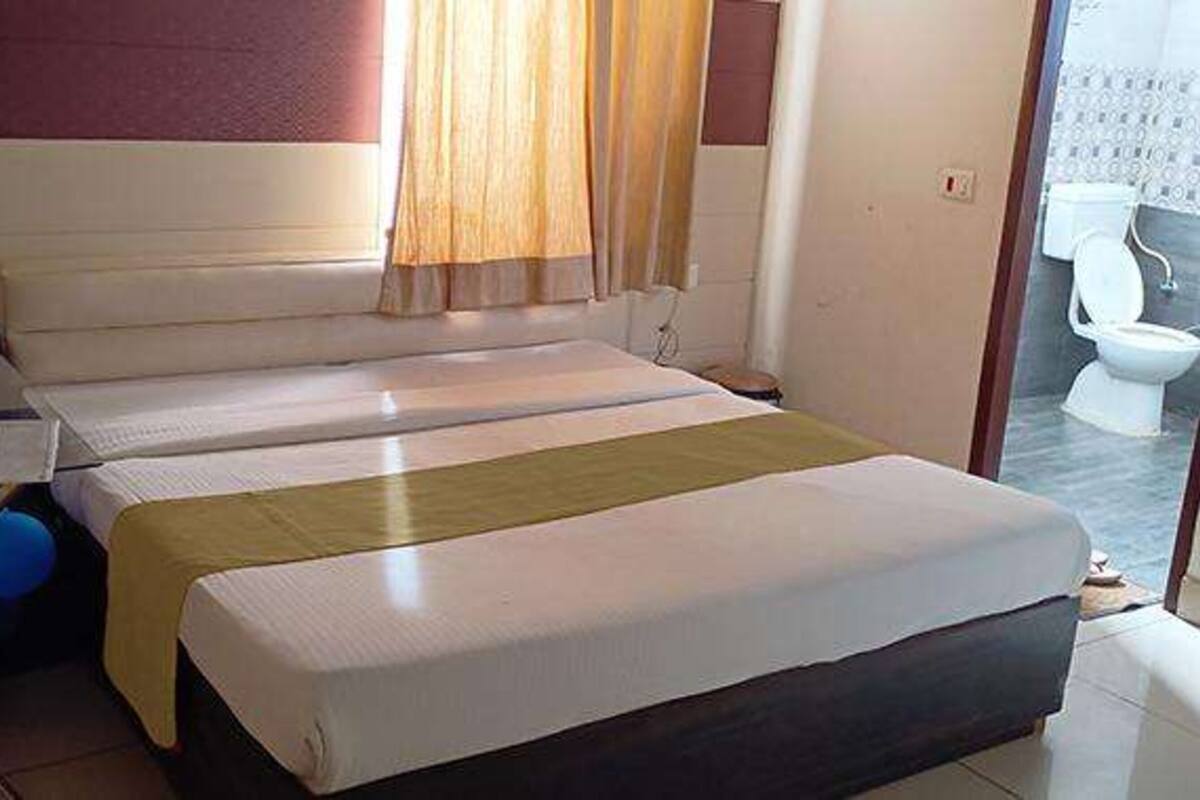A room with a bed, a desk, and a bathroom visible through an open door.