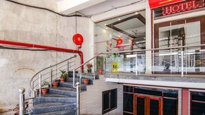 A hotel lobby with a staircase, potted plants, and a reception desk.