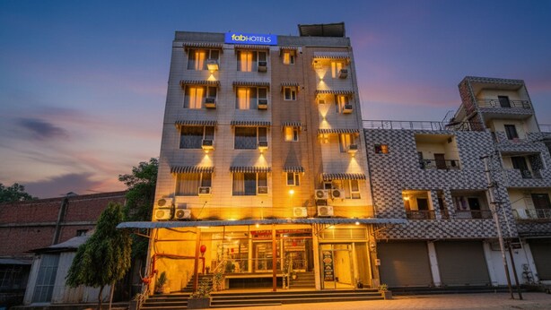 A multi-story building with a sign reading "fab hotels". It features a ground-level entrance with steps leading up to the door, multiple balconies, and air conditioning units.