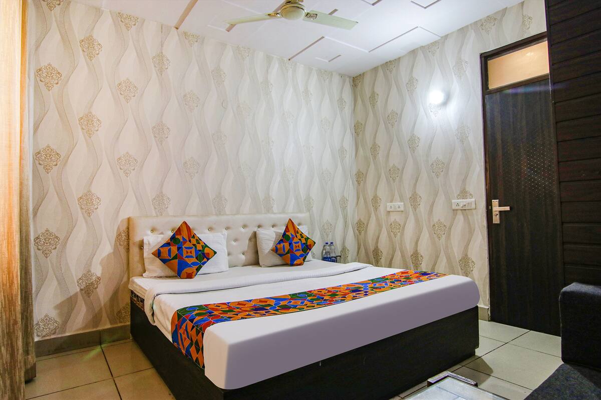 A neatly made bed with a patterned bedspread, a ceiling fan, and a door with a dark frame.