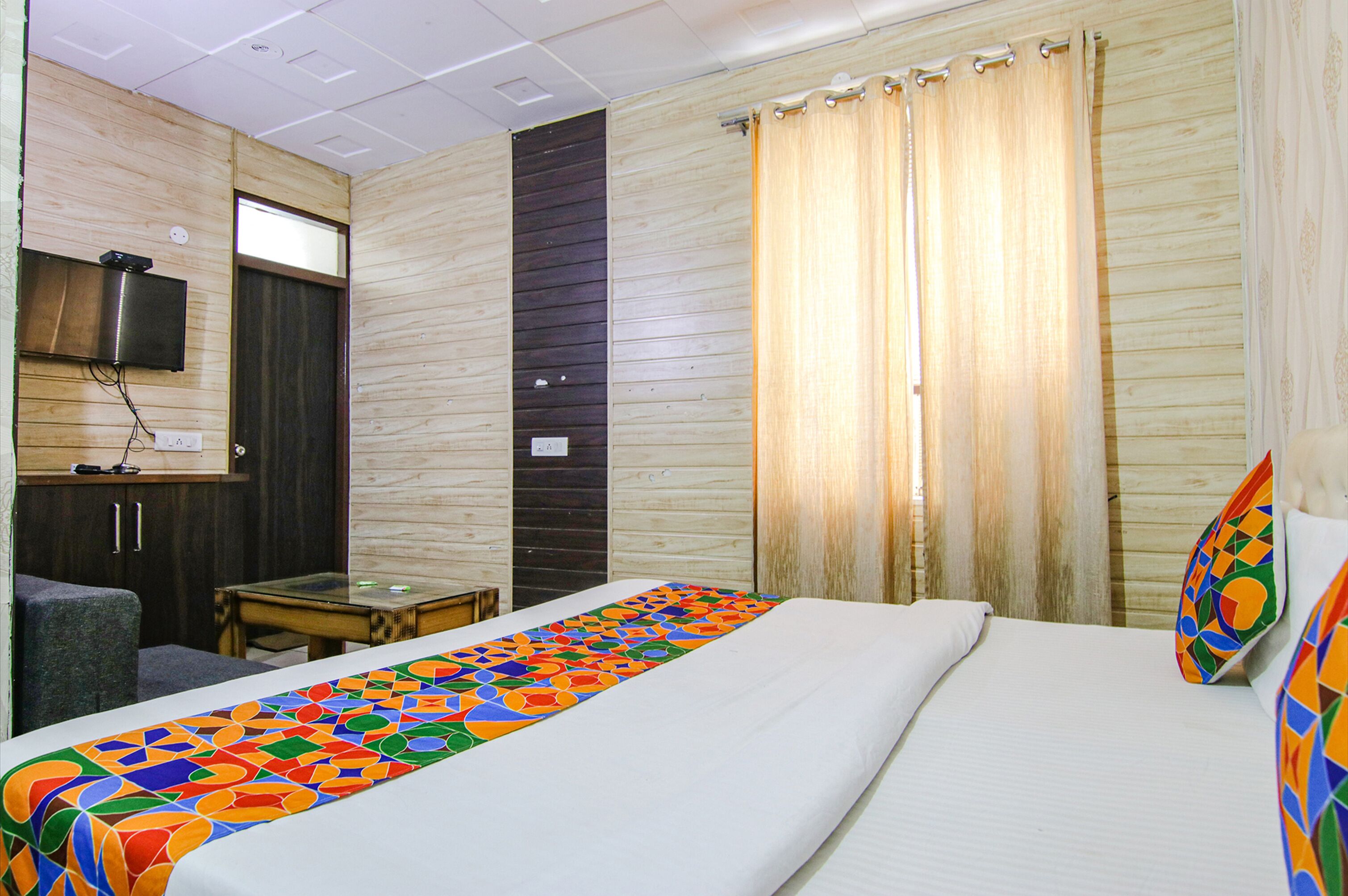 A hotel room with a bed, a TV mounted on the wall, a small table, and a chair.