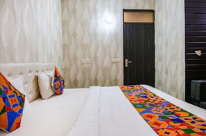 A hotel room with a bed, a headboard, and a door. - Fabhotel Gs (Mohali)