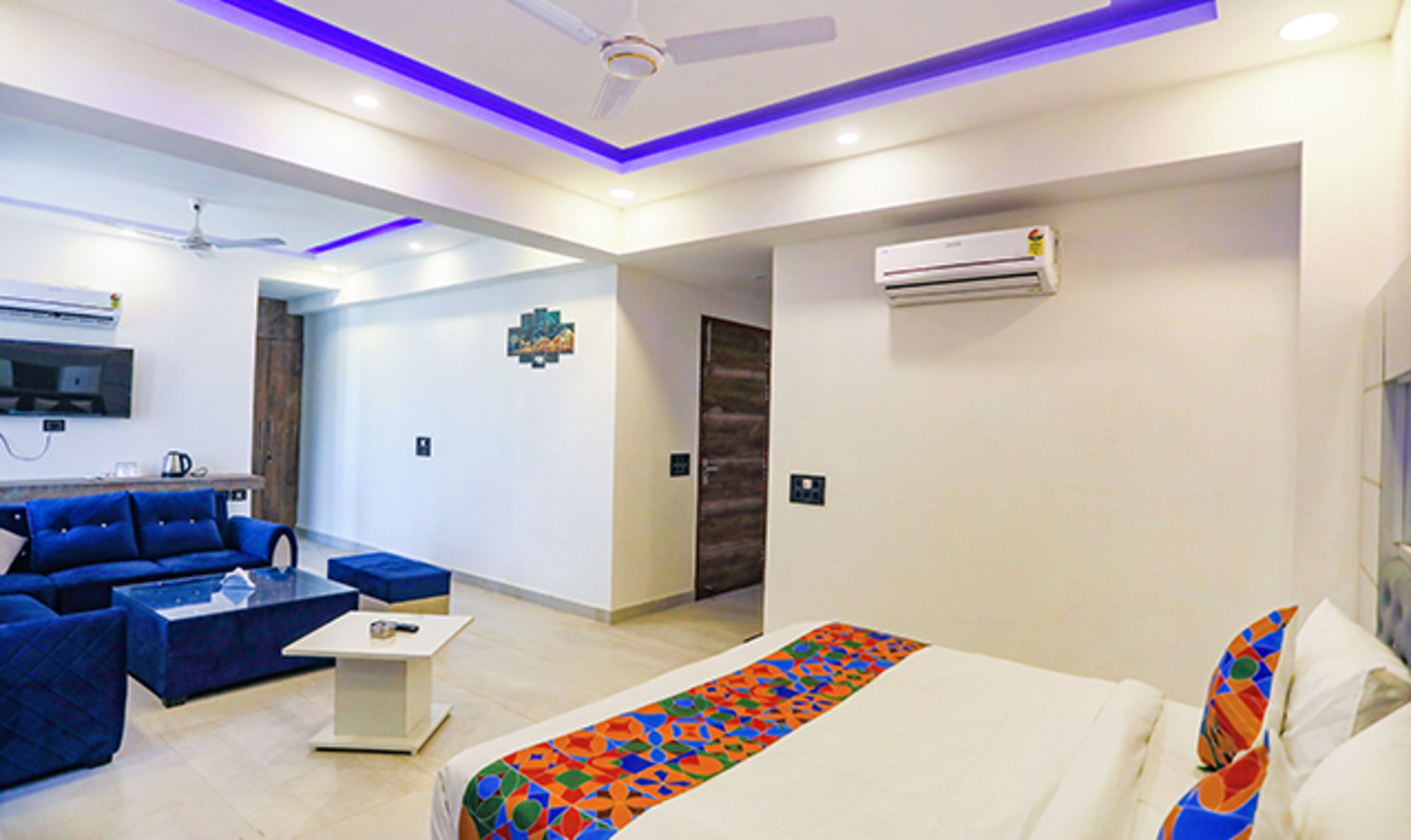 A modern hotel room with a bed, blue sofa, and a small table.