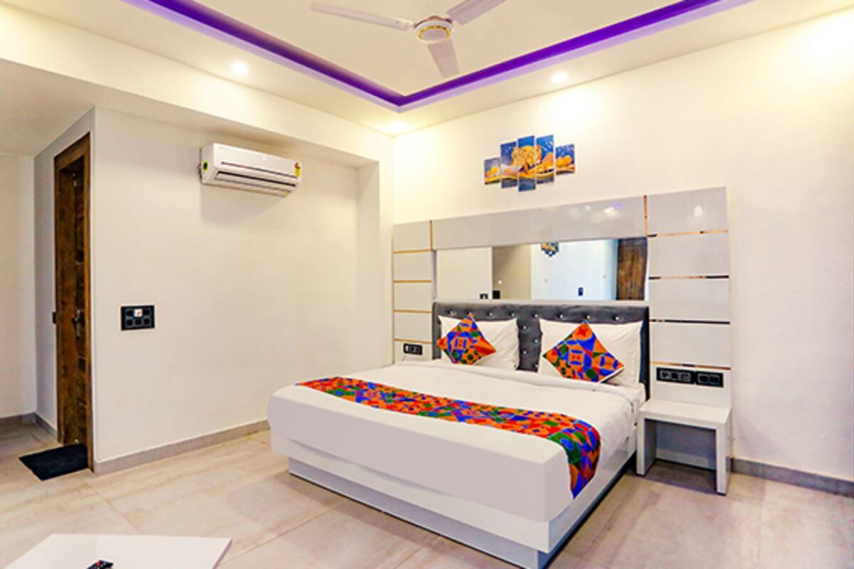 A modern hotel room with a large bed, bedside tables, an air conditioning unit, and a ceiling fan.