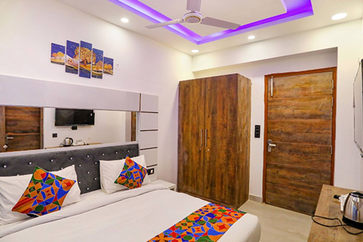 A modern bedroom with a large bed, a wooden wardrobe, and a ceiling fan.