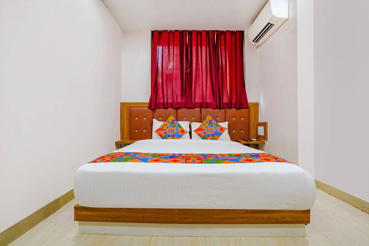 A neatly made bed with a white duvet, a wooden headboard, and two decorative pillows.