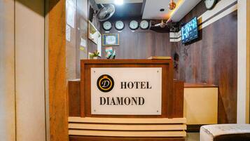 A reception desk with a sign reading "HOTEL DIAMOND" and multiple clocks on the wall.