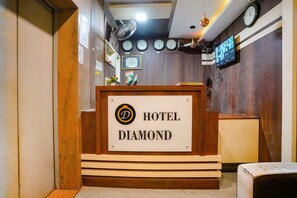 A reception desk with a sign reading "HOTEL DIAMOND" and multiple clocks on the wall. - FabExpress Diamond (Mumbai)
