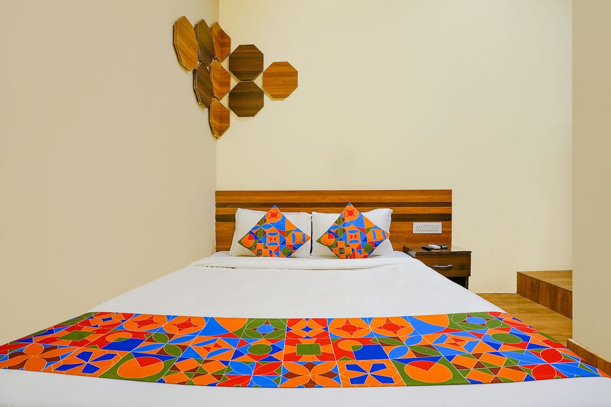 A bed with a colorful geometric-patterned bedspread, a wooden headboard, and two decorative wooden wall pieces.