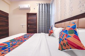 Une chambre d’hôtel avec un lit, une fenêtre avec des rideaux, un appareil de climatisation et une porte.