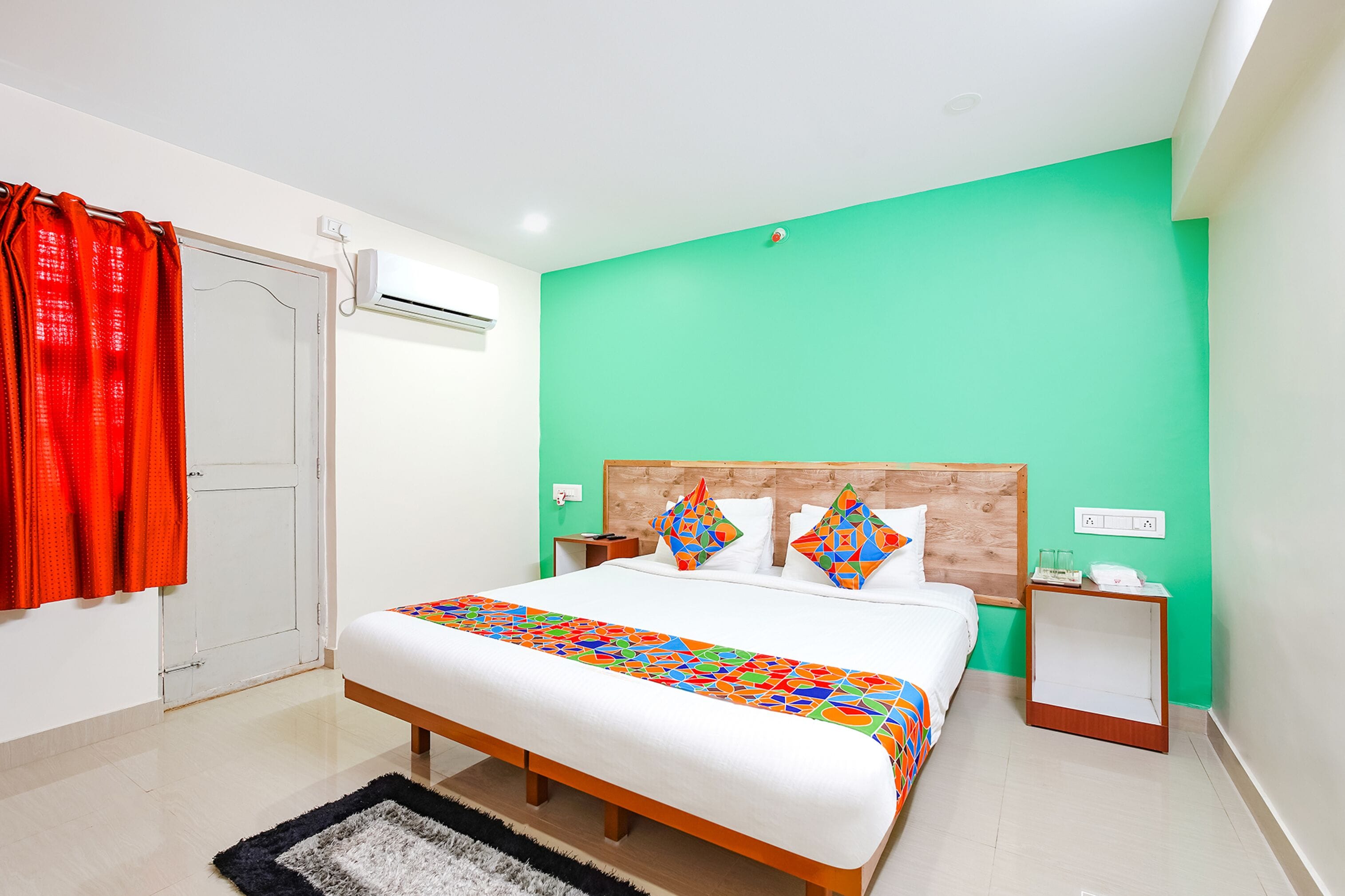 A bedroom with a bed, a nightstand, a wall-mounted air conditioner, and a door.