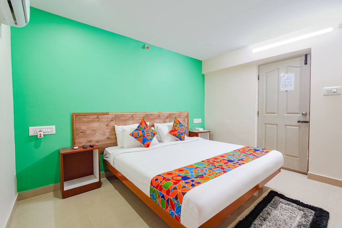 A hotel room with a large bed, green walls, a wooden headboard, and a white door.