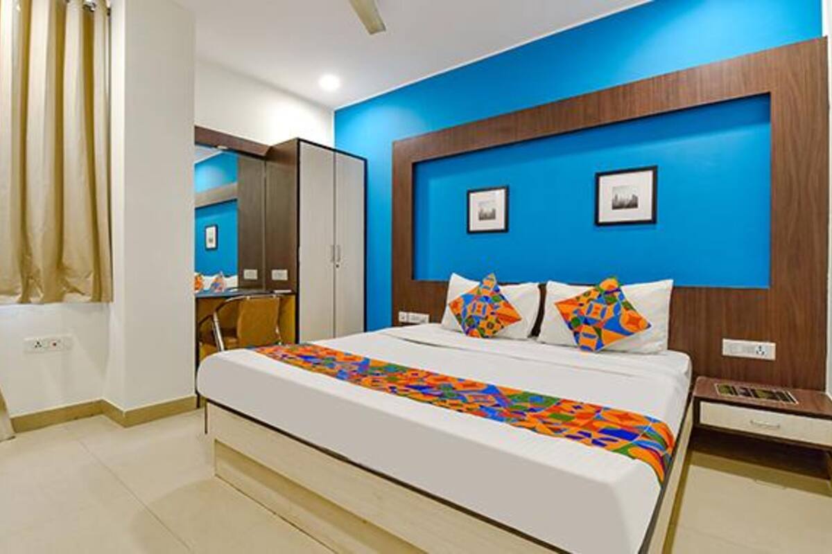 Une chambre d’hôtel avec un grand lit, une tête de lit en bois et un mur d’accent bleu.