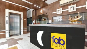 Zona de recepción de hotel con diseño moderno, que incluye un mostrador de recepción, un reloj y un ascensor.