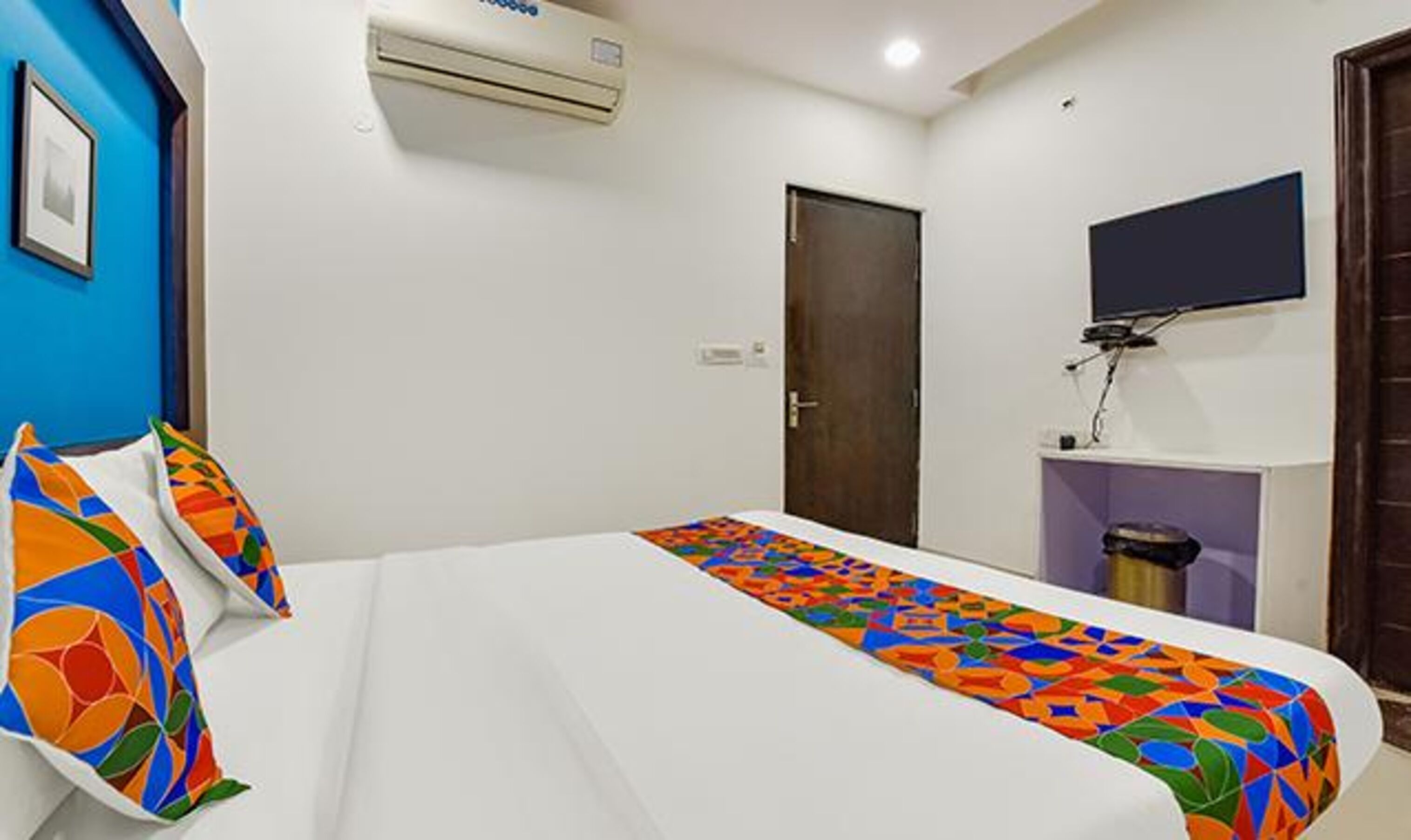 Una habitación de hotel con cama, televisión y aire acondicionado.