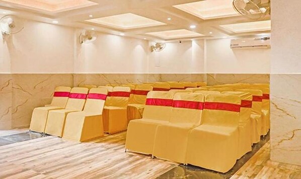 A room with rows of yellow chairs with red sashes, a marble floor, and a ceiling with recessed lighting.