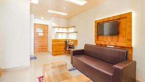 Uma sala de estar moderna com um sofá de couro marrom, uma mesa de centro de madeira e uma TV de tela plana fixada em uma parede de madeira.