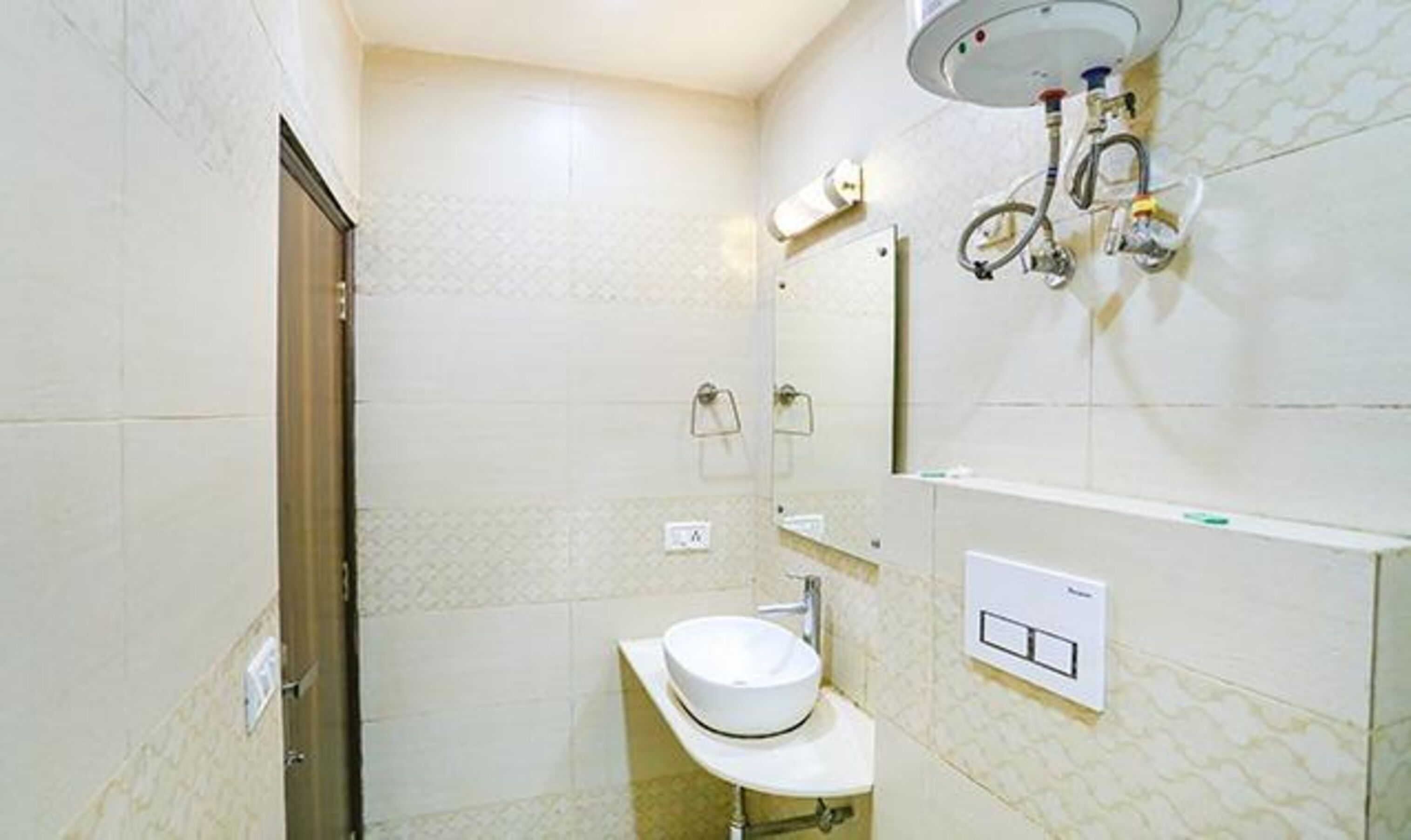A bathroom with a sink, mirror, and a wall-mounted toilet.