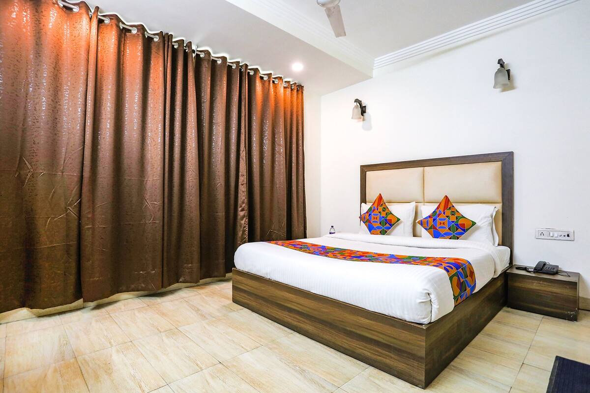 Une chambre à coucher avec un cadre de lit en bois, une couvre-lit blanche et des coussins décoratifs.