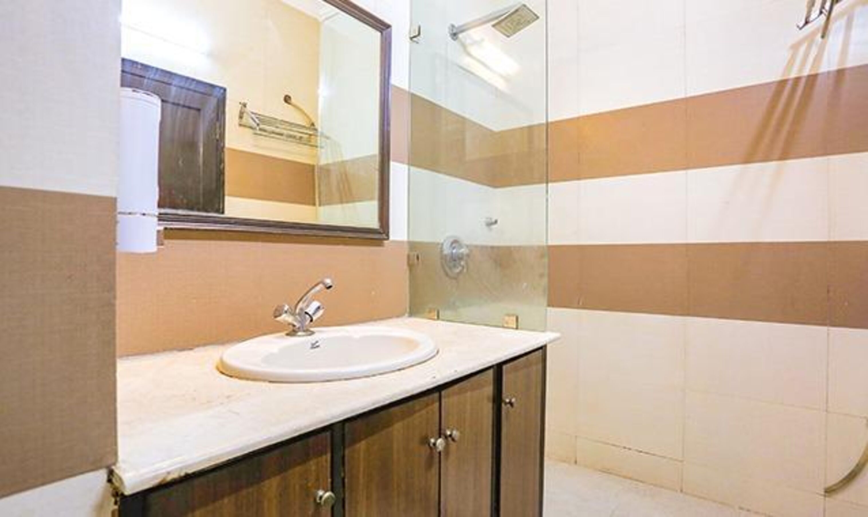 A bathroom with a sink, mirror, and shower.