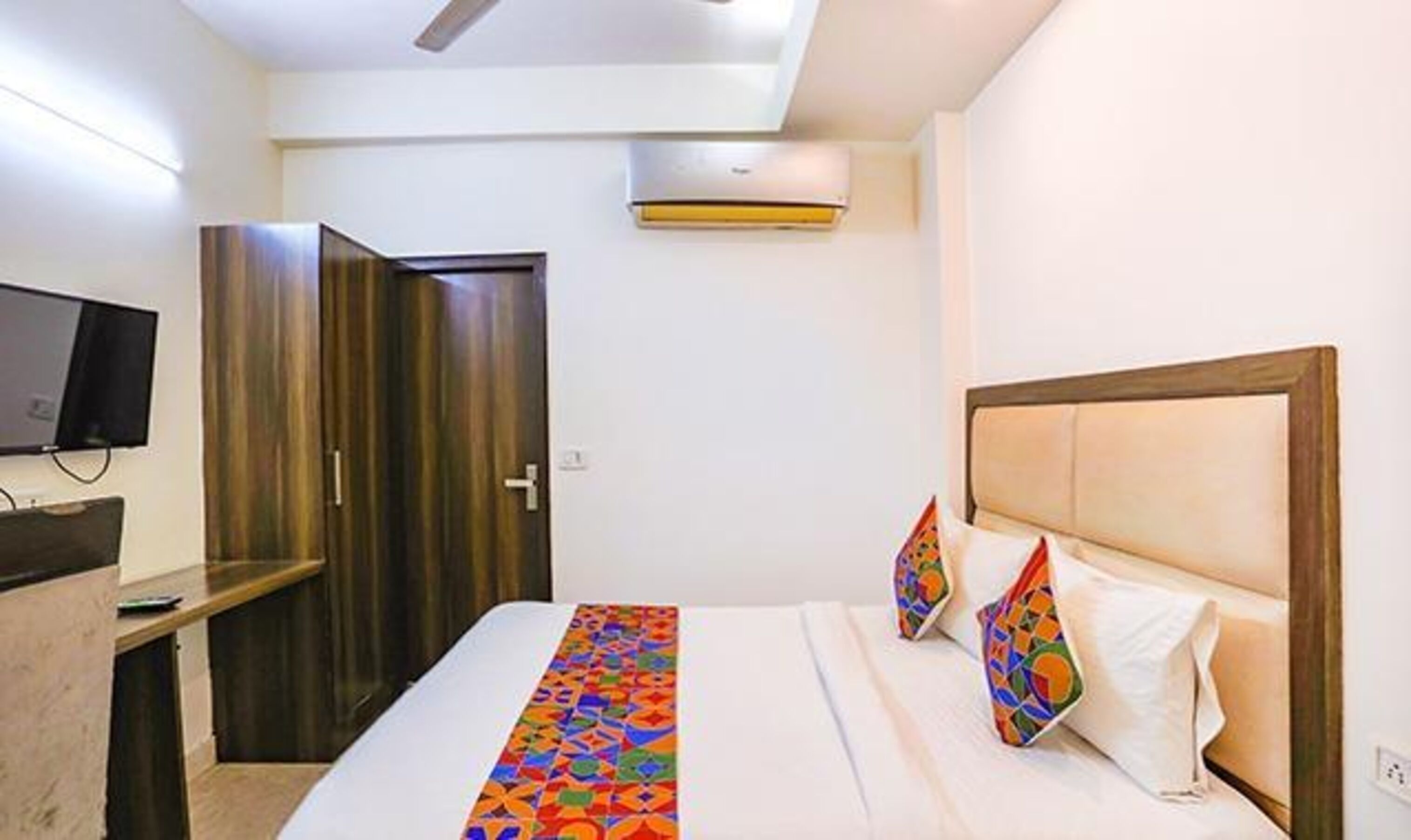 A hotel room with a bed, a desk, a TV, and a wardrobe.