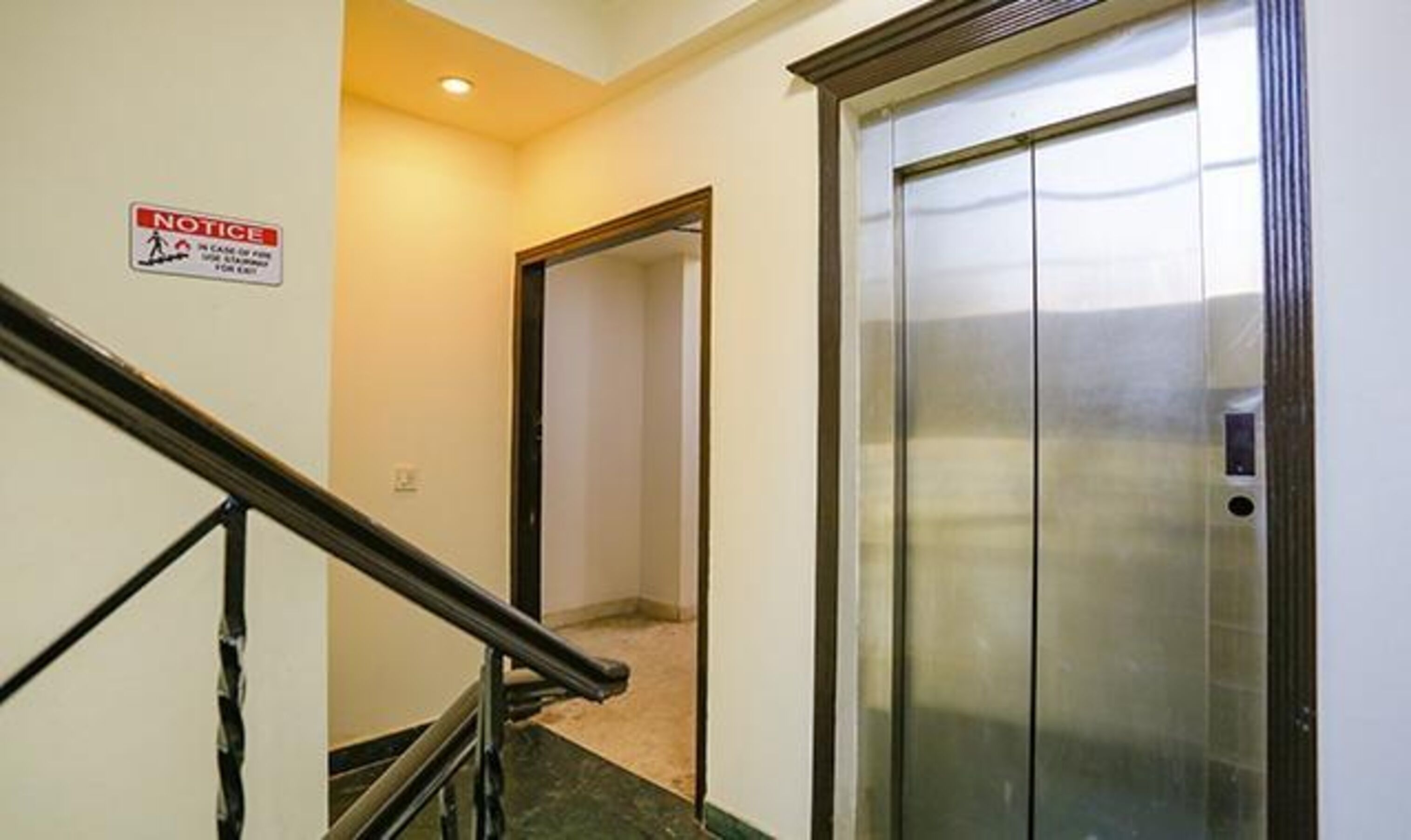 A hallway with a notice sign, a staircase, and an elevator.