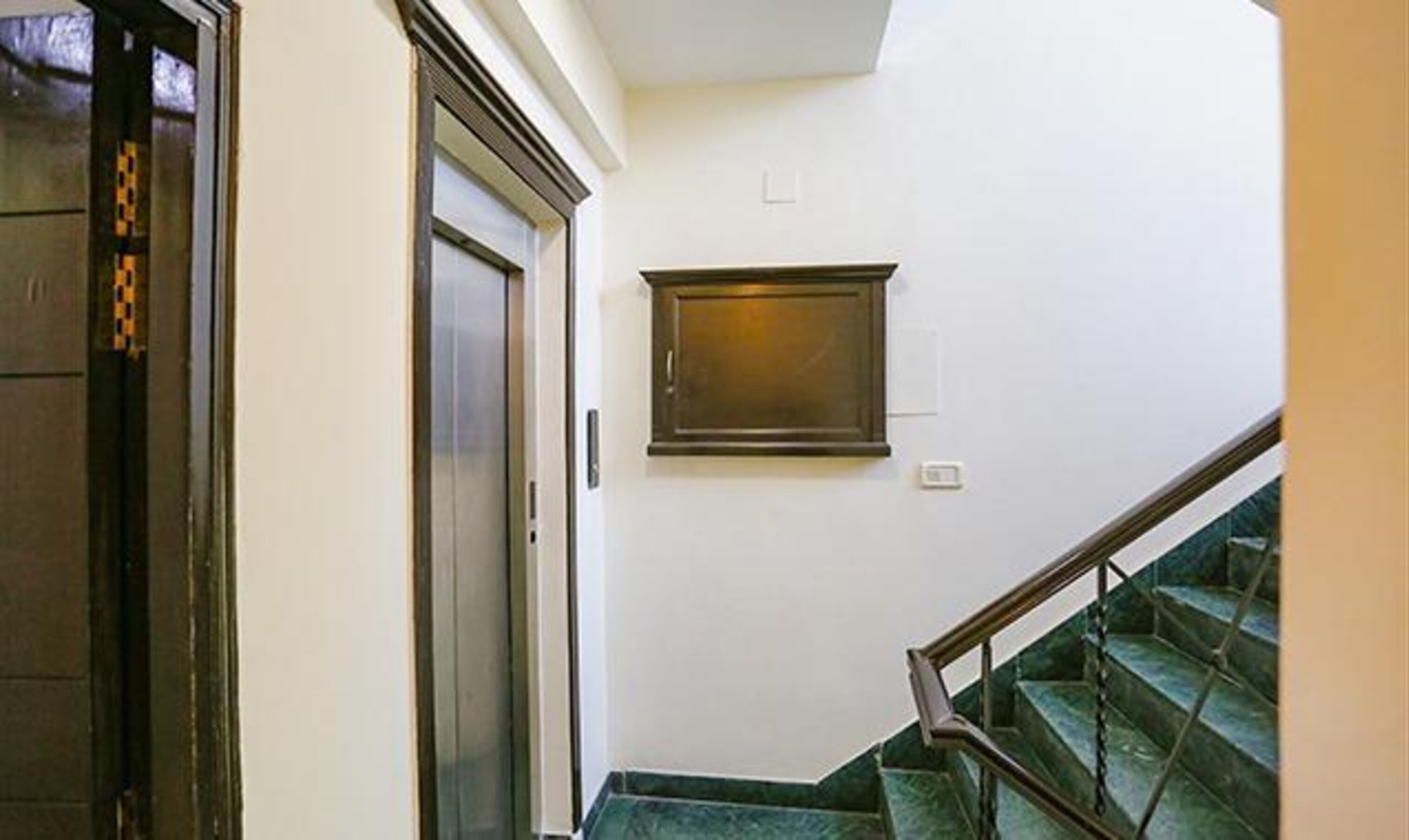 A staircase with a handrail and a door leading to an elevator.