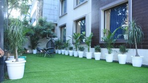 A courtyard with artificial grass, potted plants, and a seating area. - Fabhotel Posh Classic (Gurugram)