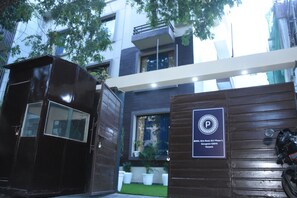 A modern building with a gated entrance, a sign indicating a parking area, and a motorcycle parked outside. - Fabhotel Posh Classic (Gurugram)