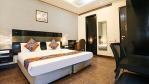 A hotel room with a large bed, a desk, a chair, and a mirror. - Fabhotel Posh Classic (Gurugram)