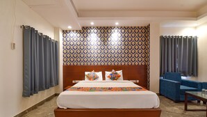 A hotel room with a large bed, a wooden headboard, a patterned wall, and a blue armchair. - Fabhotel Wind Palace (Jaipur)