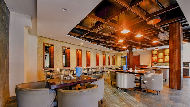 A modern hotel lobby with a bar area, seating arrangements, and a kitchen visible in the background. - Fabhotel Wind Palace (Jaipur)