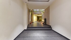 A hallway with a staircase leading to a room. The walls are adorned with a patterned wallpaper and green plants. - Fabhotel Wind Palace (Jaipur)