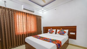 A hotel room with a wooden bed, white bedding, and colorful pillows. - Fabhotel Whitefield Suites (Bengaluru)