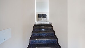 A set of black marble stairs with a handrail leading to a landing where two black chairs are placed. - Fabhotel Whitefield Suites (Bengaluru)