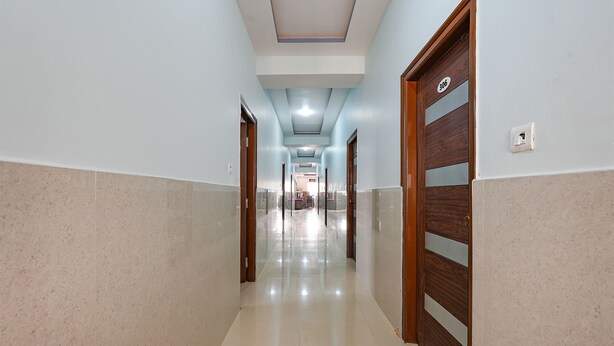 A hallway with a polished floor, light blue walls, and wooden doors with glass panels. - Fabhotel Whitefield Suites (Bengaluru)