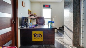 A hotel reception desk with a wooden finish, a clock on the wall, and a sign indicating the hotel's name. - Fabhotel Whitefield Suites (Bengaluru)